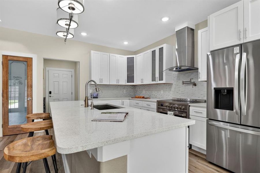 Quartz white countertops, breakfast bar, pot filler over 36"inch stainless steel oversized stove for gourmet cooking, and designer lightning.
