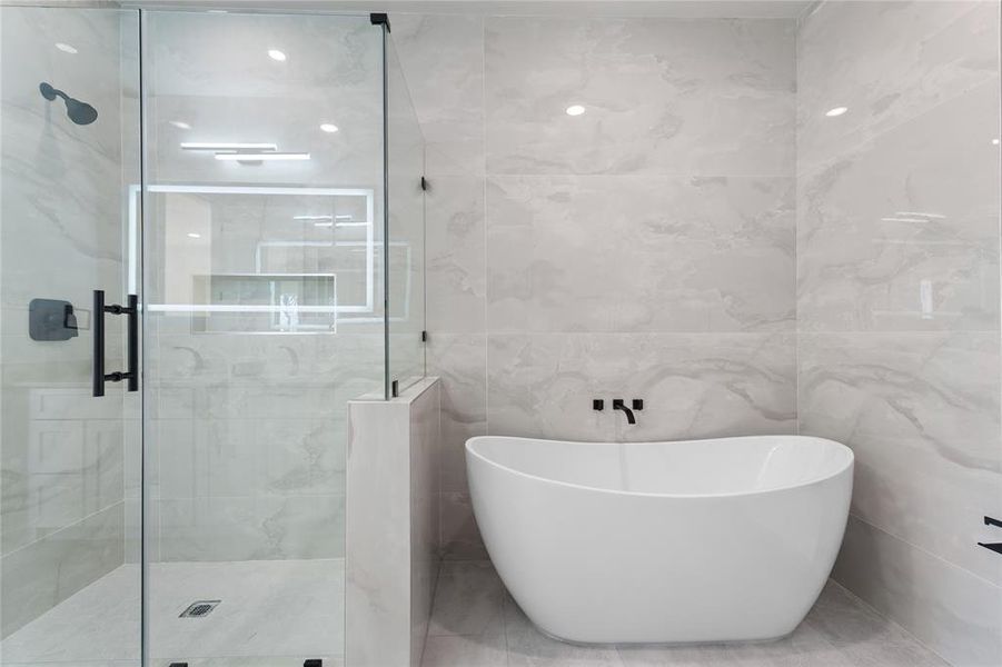 Full bathroom with tile walls, a shower stall, and a freestanding bath