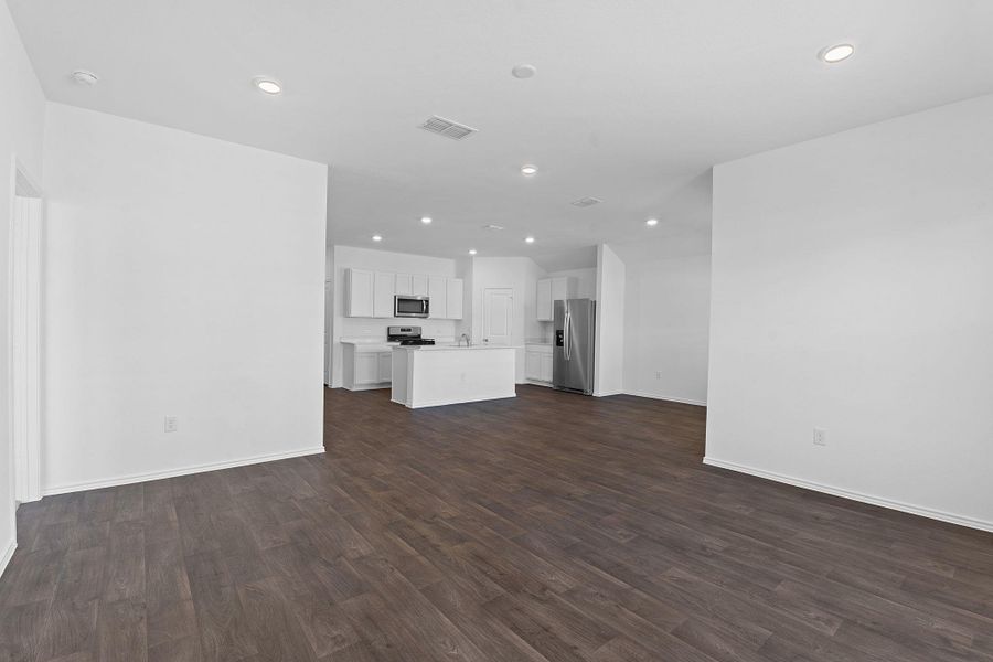 Unfurnished living room featuring recessed lighting, visible vents, dark wood finished floors, and baseboards