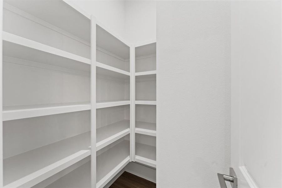 This photo shows a spacious, well-lit pantry with multiple white shelves, perfect for organized storage of kitchen essentials.