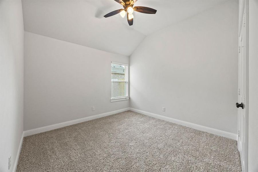 Spare room with vaulted ceiling, carpet flooring, and ceiling fan