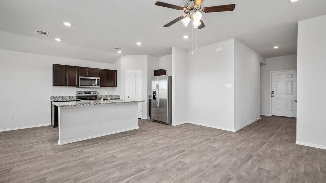Kitchen featuring dark brown cabinets, stainless steel appliances, an island with sink, light wood-style flooring, and a ceiling fan