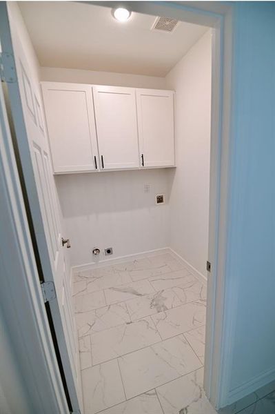 Clothes washing area featuring hookup for an electric dryer, washer hookup, cabinets, and light tile patterned floors