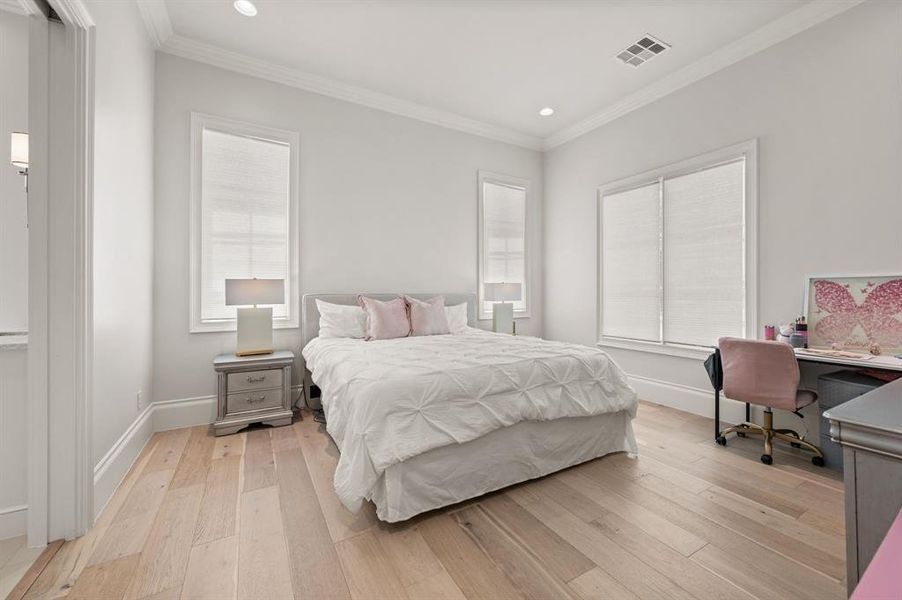 Bedroom featuring recessed lighting, light wood finished floors, crown molding, multiple windows, and an office area Bedroom featuring recessed lighting, light wood finished floors, crown molding, multiple windows, and an office area