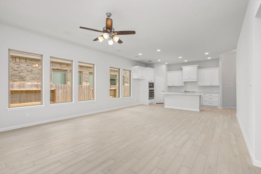 Bright open-concept living room and kitchen with wood-look tile flooring and modern finishes.