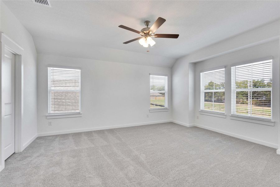 Empty room with light colored carpet, a ceiling fan, and vaulted ceiling
