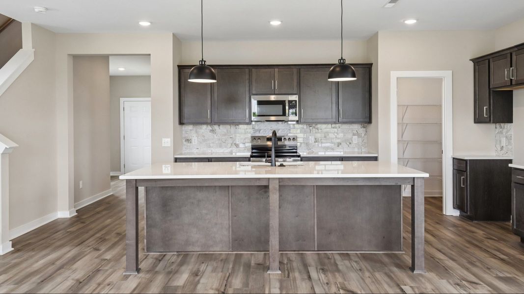 Kitchen with dark cabinetry, quartz countertops, and tile backsplash