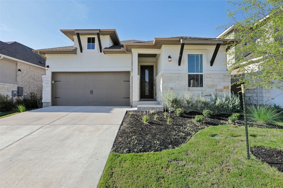 Prairie-style home with a garage, stone siding, driveway, and stucco siding