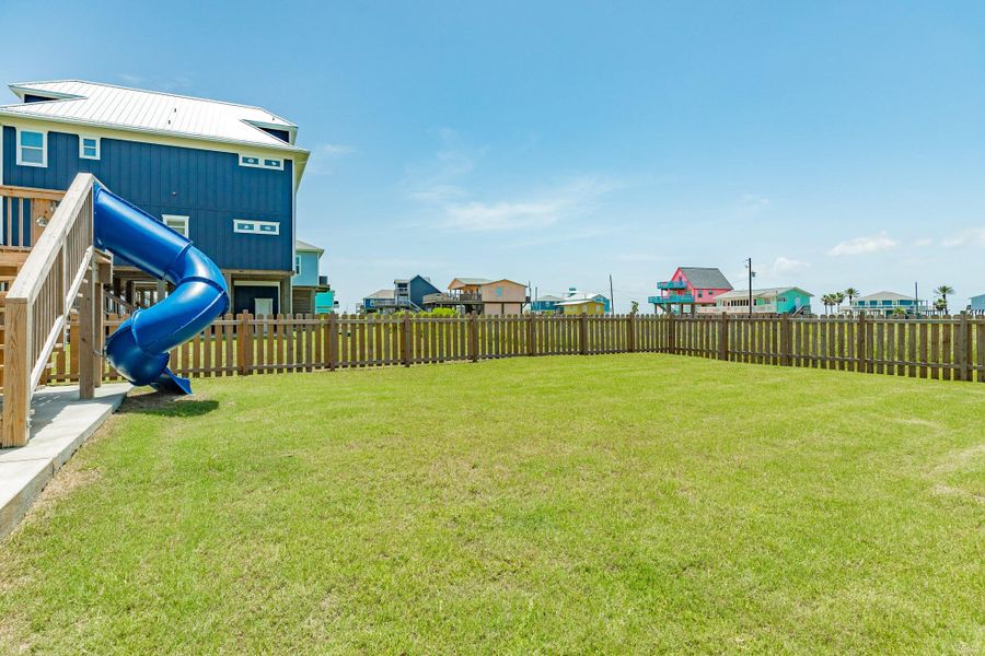 Spacious fenced backyard offers plenty of room for outdoor games, pets, and gatherings, with the spiral slide adding a fun touch.
