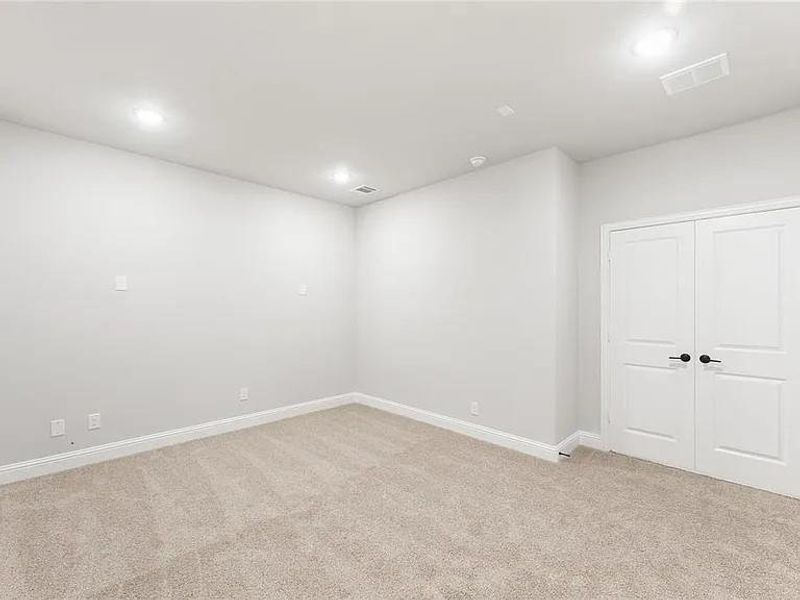 Empty room featuring light colored carpet, baseboards, and recessed lighting