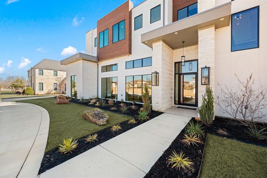 View of exterior entry with meticulous landscaping