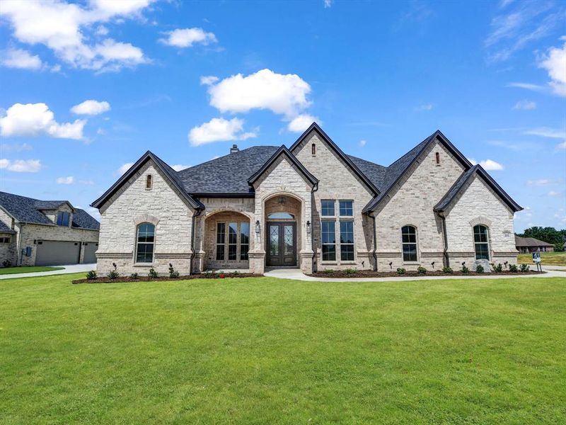 French country home featuring a garage and a front yard