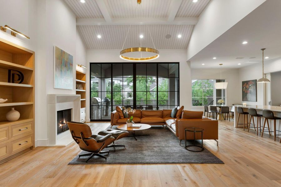 Bright living area with vaulted beamed ceilings, a sleek fireplace, and expansive patio doors that open to the covered outdoor living space and pool area.