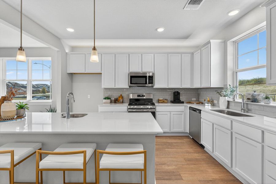 Kitchen featuring white cabinets, tasteful backsplash, hanging light fixtures, light stone countertops, and recessed lighting