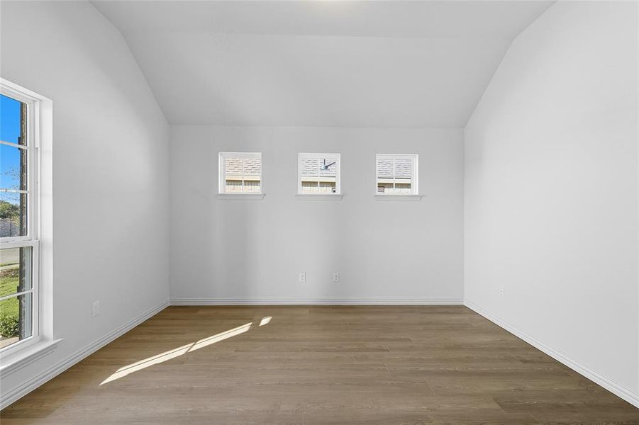 Spare room with wood finished floors and vaulted ceiling Spare room with wood finished floors and vaulted ceiling