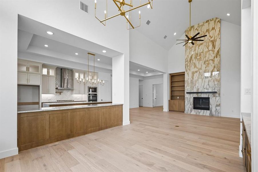 Kitchen featuring a chandelier, high vaulted ceiling, open floor plan, decorative light fixtures, and glass insert cabinets Kitchen featuring a chandelier, high vaulted ceiling, open floor plan, decorative light fixtures, and glass insert cabinets