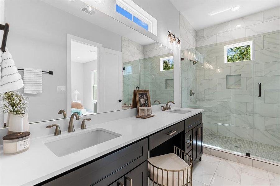 In the primary bathroom, dual vanity sinks complement a makeup nook, while the oversized shower features ceramic mosaic tile and glistening white marble polished tile.