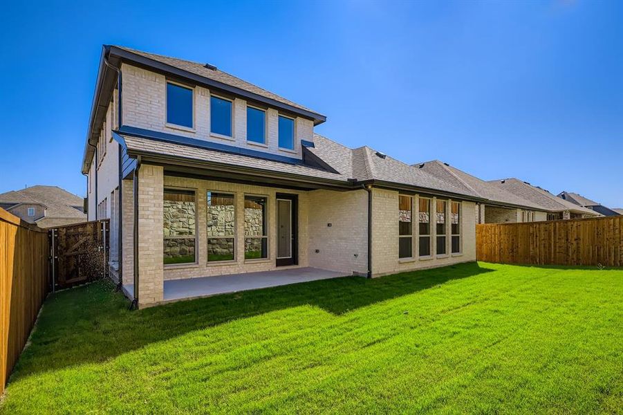 Back of property featuring brick siding, a fenced backyard, a patio area, and a shingled roof
