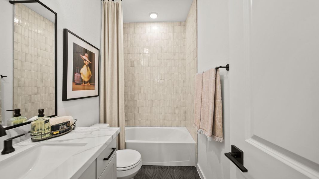 These secondary bathrooms are certainly not secondary in style! Marbled porcelain countertops complimented by lovely grey cabinetry and a striking tile detailed on the bathtub walls give this bathroom a clean, crisp feeling. To finish the space off, a matte black herringbone tile compliments the floor. These secondary bathrooms are certainly not secondary in style! Marbled porcelain countertops complimented by lovely grey cabinetry and a striking tile detailed on the bathtub walls give this bathroom a clean, crisp feeling. To finish the space off, a matte black herringbone tile compliments the floor.