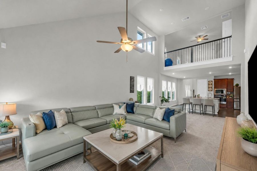 The expansive family room features an airy loft overlook with iron railings, a towering vaulted ceiling, and an open layout leading directly into the kitchen.**Virtually staged The expansive family room features an airy loft overlook with iron railings, a towering vaulted ceiling, and an open layout leading directly into the kitchen.**Virtually staged