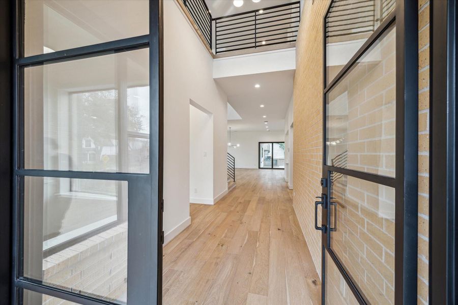 Steel and glass entry door opens to wide entrance hall