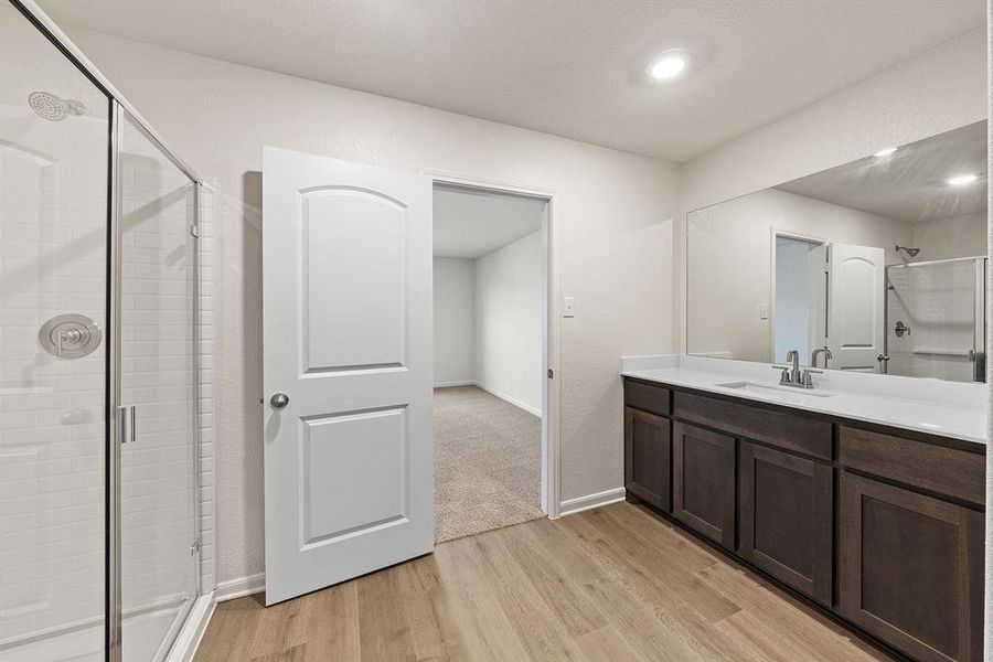 Full bathroom featuring a stall shower, vanity, baseboards, and wood finished floors