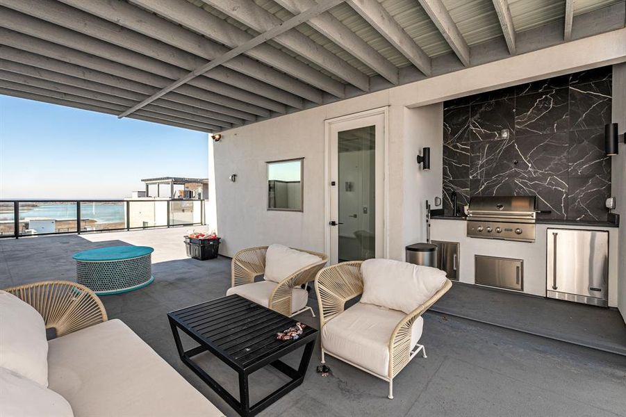 View of patio / terrace with grilling area, an outdoor hangout area, a water view, and an outdoor kitchen