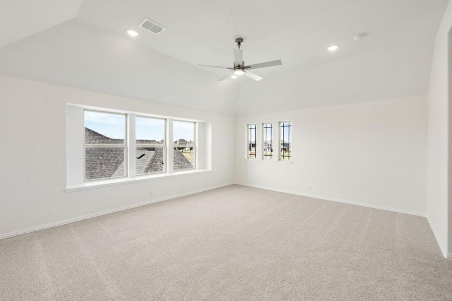 Empty bedroom with vaulted ceiling, ceiling fan, carpet flooring, and large windows Empty bedroom with vaulted ceiling, ceiling fan, carpet flooring, and large windows