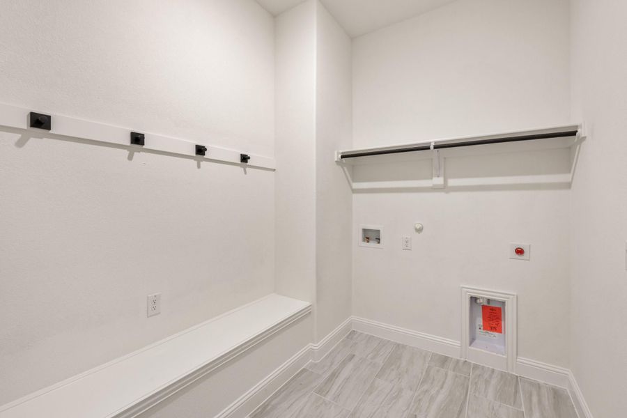 Laundry room with white walls, hanging rods, built-in bench, and washer and dryer hookups on tile floor Laundry room with white walls, hanging rods, built-in bench, and washer and dryer hookups on tile floor