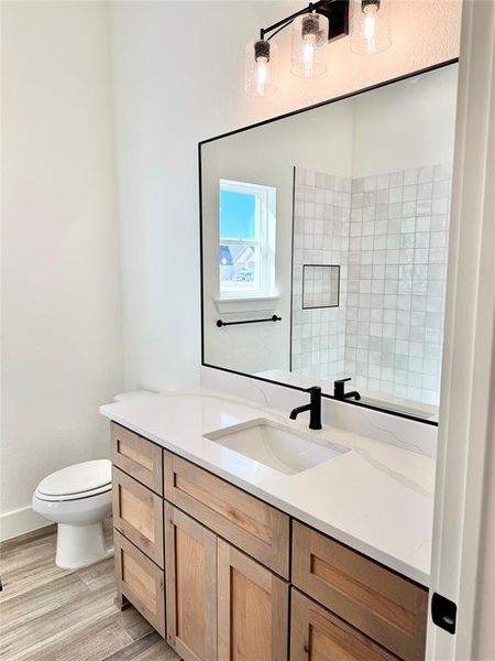 Bathroom featuring toilet, baseboards, wood finished floors, and vanity