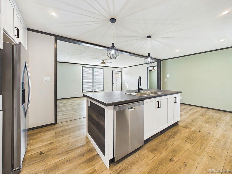 Kitchen – Stylish open-concept kitchen featuring a large island with seating, pendant lighting, stainless steel appliances, and modern cabinetry.