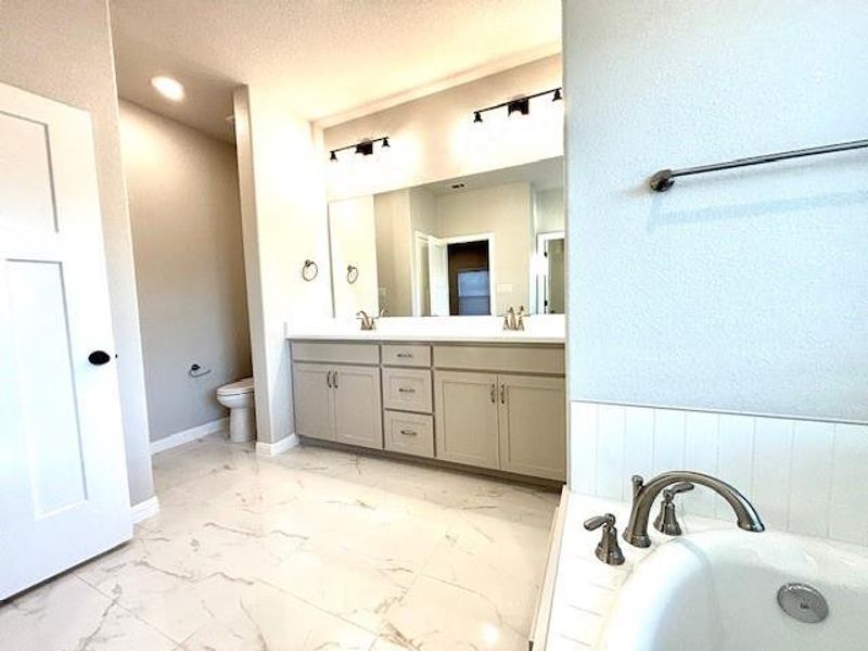 Bathroom featuring a textured ceiling, vanity, toilet, and a bathtub