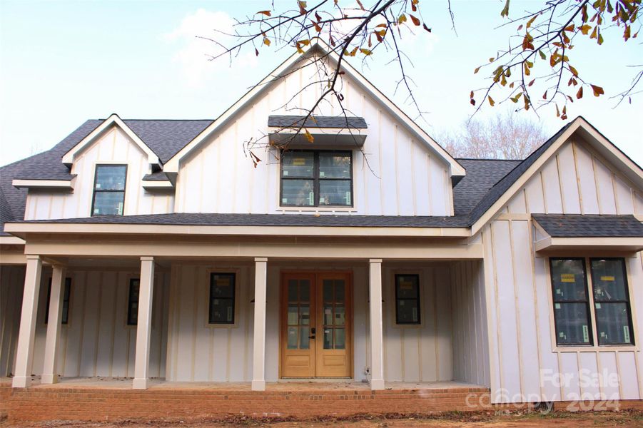 Modern farmhouse with inviting porch and charming double doors.