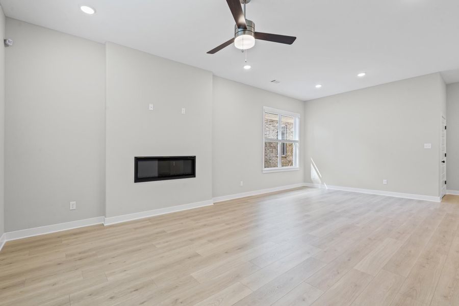 Unfurnished living room with recessed lighting, a glass covered fireplace, light wood-style floors, and ceiling fan
