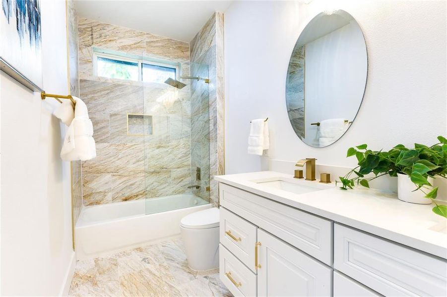 Full bathroom with tiled shower / bath, vanity, and toilet