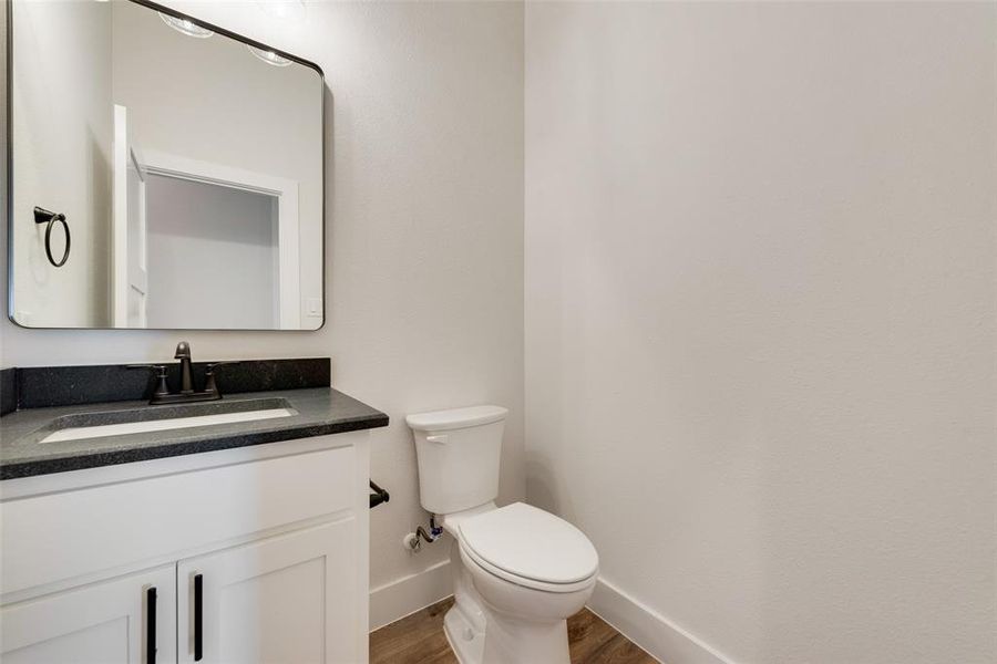 Bathroom featuring a white vanity with black hardware, dark countertop, rectangular undermount sink, and black faucet