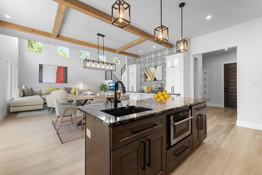 Kitchen featuring a sink, beam ceiling, light wood-style floors, dark brown cabinetry, and dark stone counters Kitchen featuring a sink, beam ceiling, light wood-style floors, dark brown cabinetry, and dark stone counters
