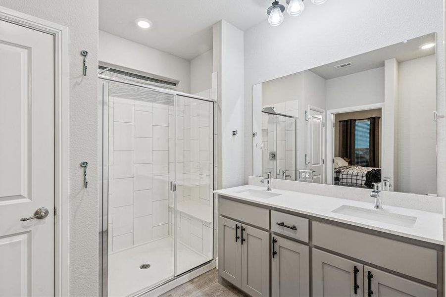 Primary bathroom with a shower stall, ensuite bath, double vanity, and wood finished floors Primary bathroom with a shower stall, ensuite bath, double vanity, and wood finished floors