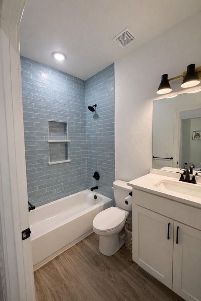 Full bathroom featuring shower / washtub combination, vanity, and dark wood-style floors Full bathroom featuring shower / washtub combination, vanity, and dark wood-style floors