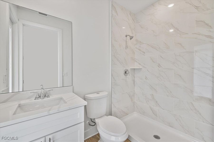 Full bath with a marble finish shower and vanity