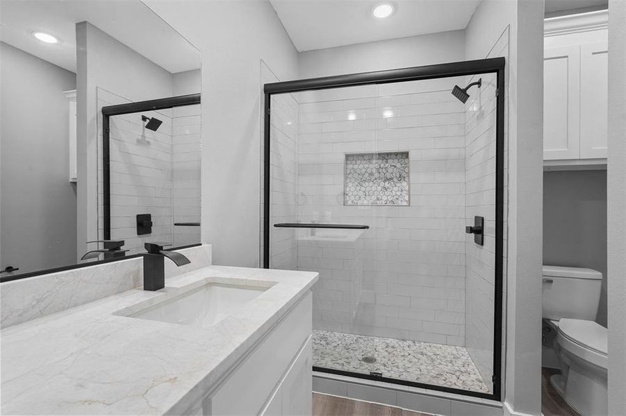 Bathroom featuring hardwood / wood-style floors, vanity, toilet, and a shower with shower door