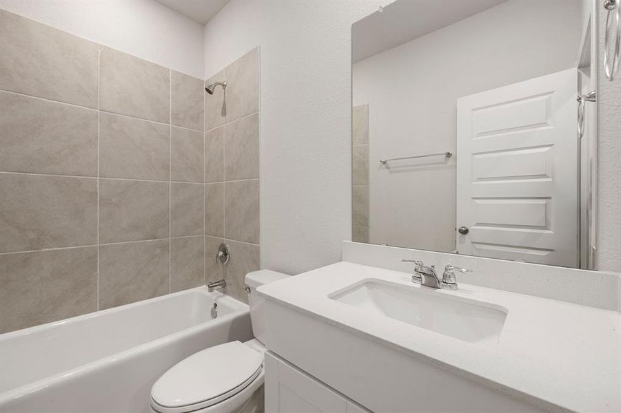 Secondary bath features tile flooring, bath/shower combo with tile surround, bright cabinets, beautiful Quartz countertops, mirror, sleek fixtures and modern finishes.