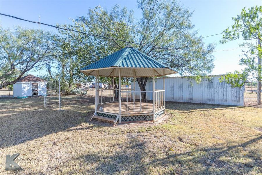 View of yard featuring a gazebo, a wooden deck, and an outbuilding View of yard featuring a gazebo, a wooden deck, and an outbuilding