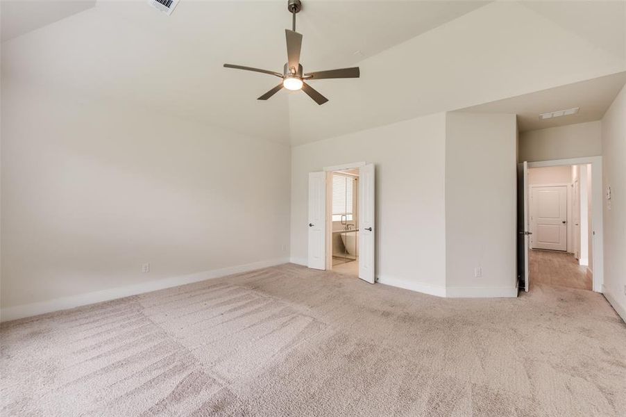 Unfurnished bedroom with light colored carpet, baseboards, high vaulted ceiling, ensuite bathroom, and ceiling fan Unfurnished bedroom with light colored carpet, baseboards, high vaulted ceiling, ensuite bathroom, and ceiling fan