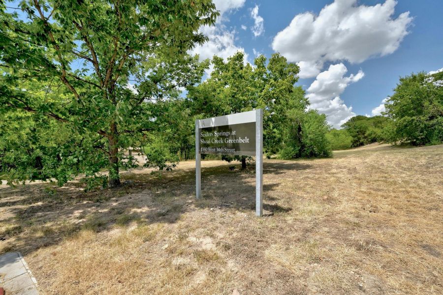 Informational sign for "Cedar Springs at Shoal Creek Greenbelt" with surrounding natural landscape