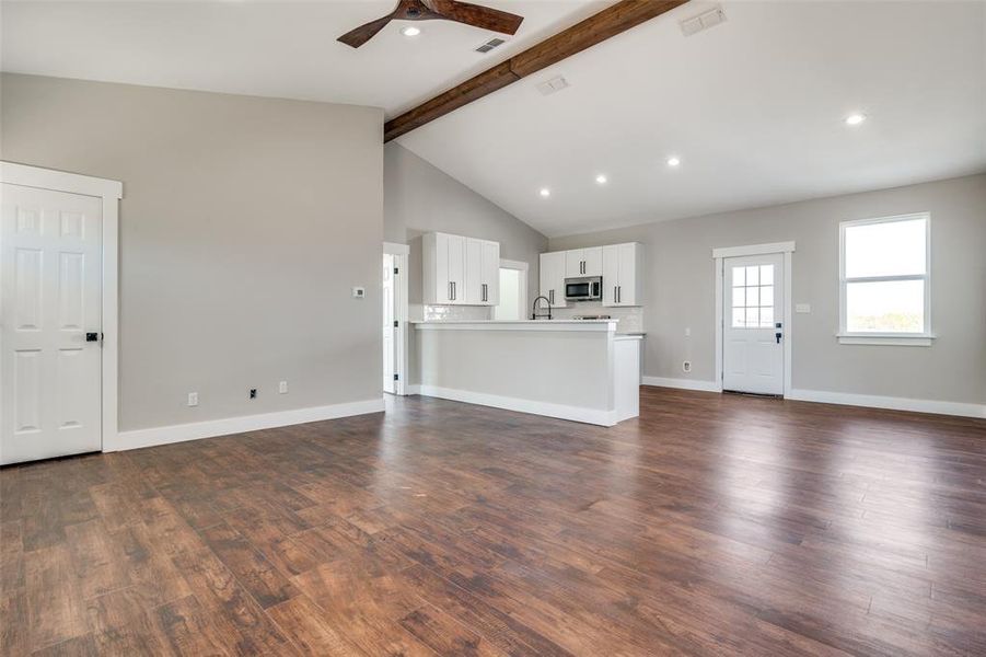 Unfurnished living room featuring beam ceiling, dark hardwood / wood-style flooring, ceiling fan, and sink