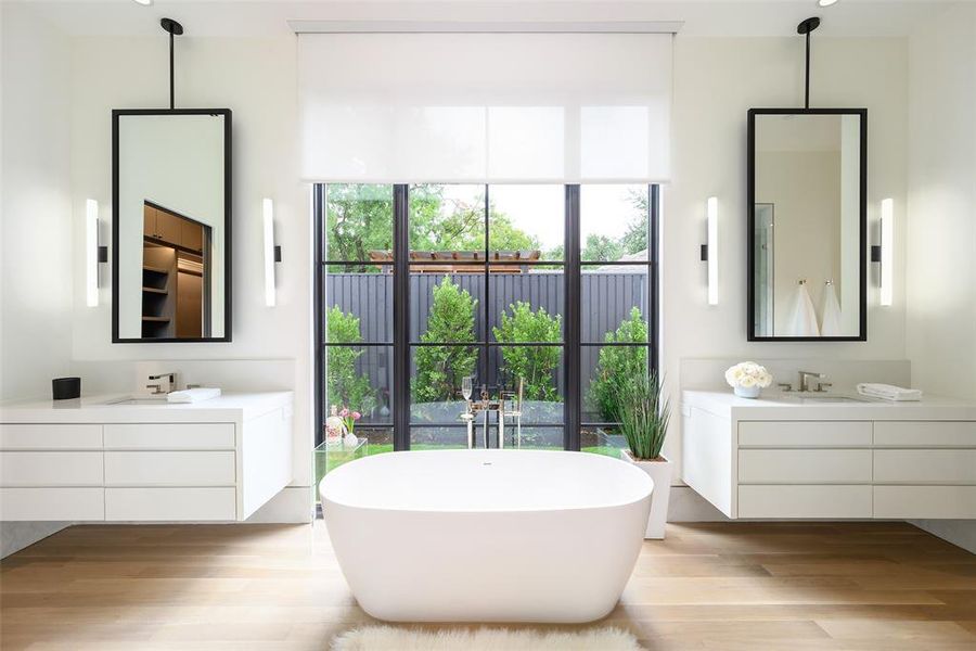 Full bathroom with a freestanding tub, two vanities, and light wood finished floors Full bathroom with a freestanding tub, two vanities, and light wood finished floors
