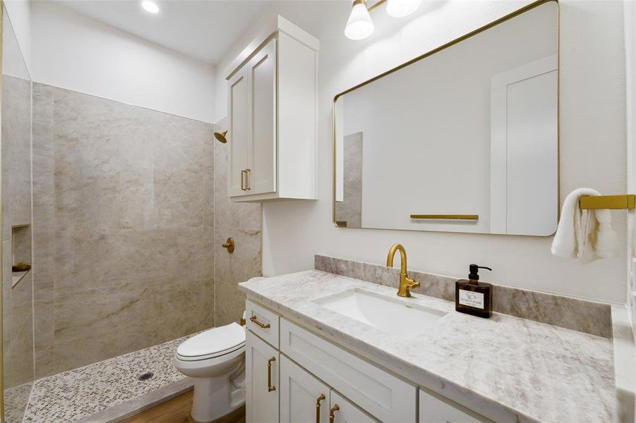 Bathroom featuring a white shaker vanity with a light-toned countertop, an undermount sink, and brass-finish fixtures