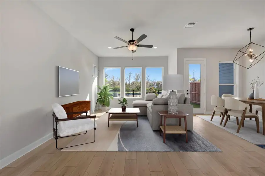 Living room featuring hanging lights, light wood-type flooring, and a ceiling fan Living room featuring hanging lights, light wood-type flooring, and a ceiling fan