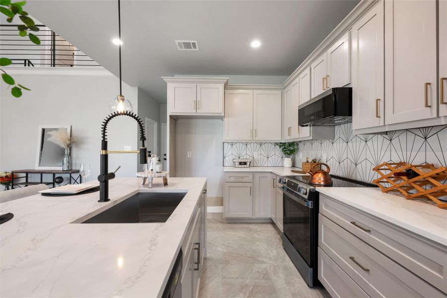 Kitchen featuring electric range, decorative backsplash, pendant lighting, light stone counters, and recessed lighting